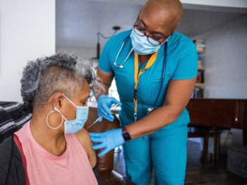 Black woman receiving COVID vaccine, representing the nurse staffing tile image