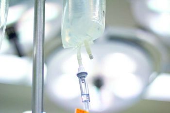 An IV (intravenous) bag containing life sustaining fluid hangs on a pole in the operating room. (14MP camera